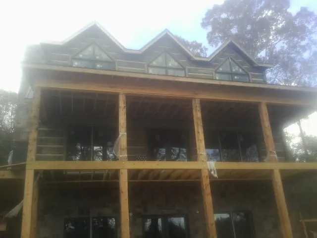 Dormers and porch framing on a large log home under construction — Roof Coating work by our crew in Hannibal